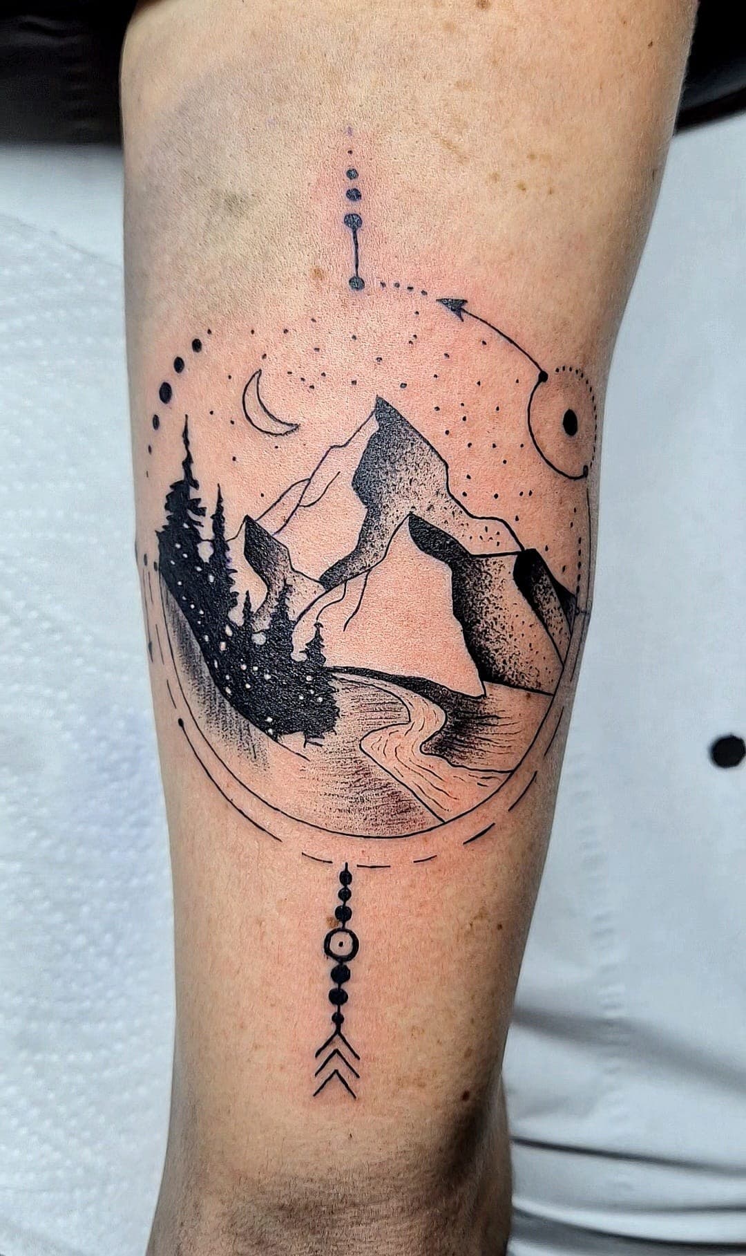 Paysage de montagne en ligne fine et dotwork tatoué sur le mollet