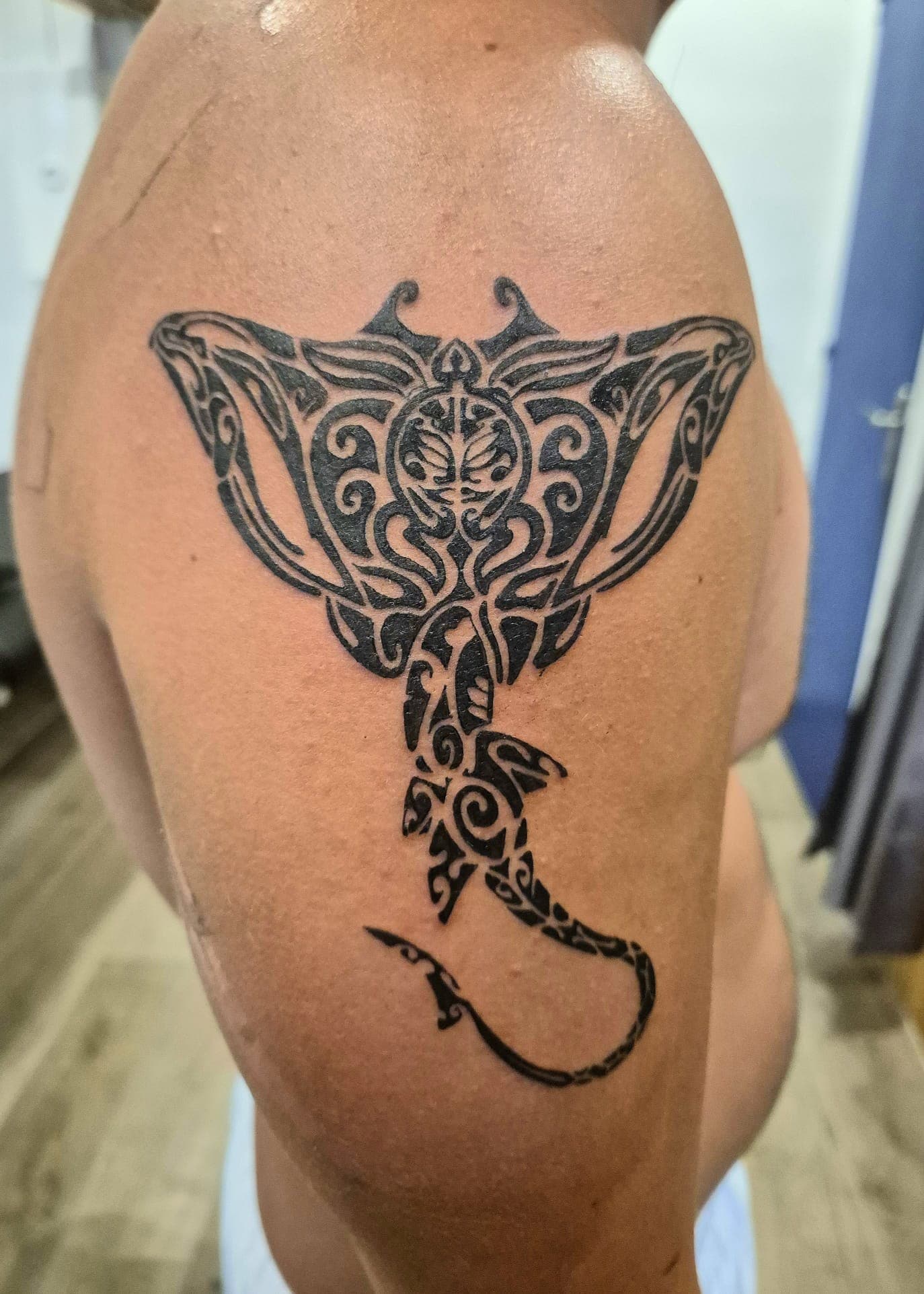Raie manta aux motifs polynésiens tatouée sur le haut du dos